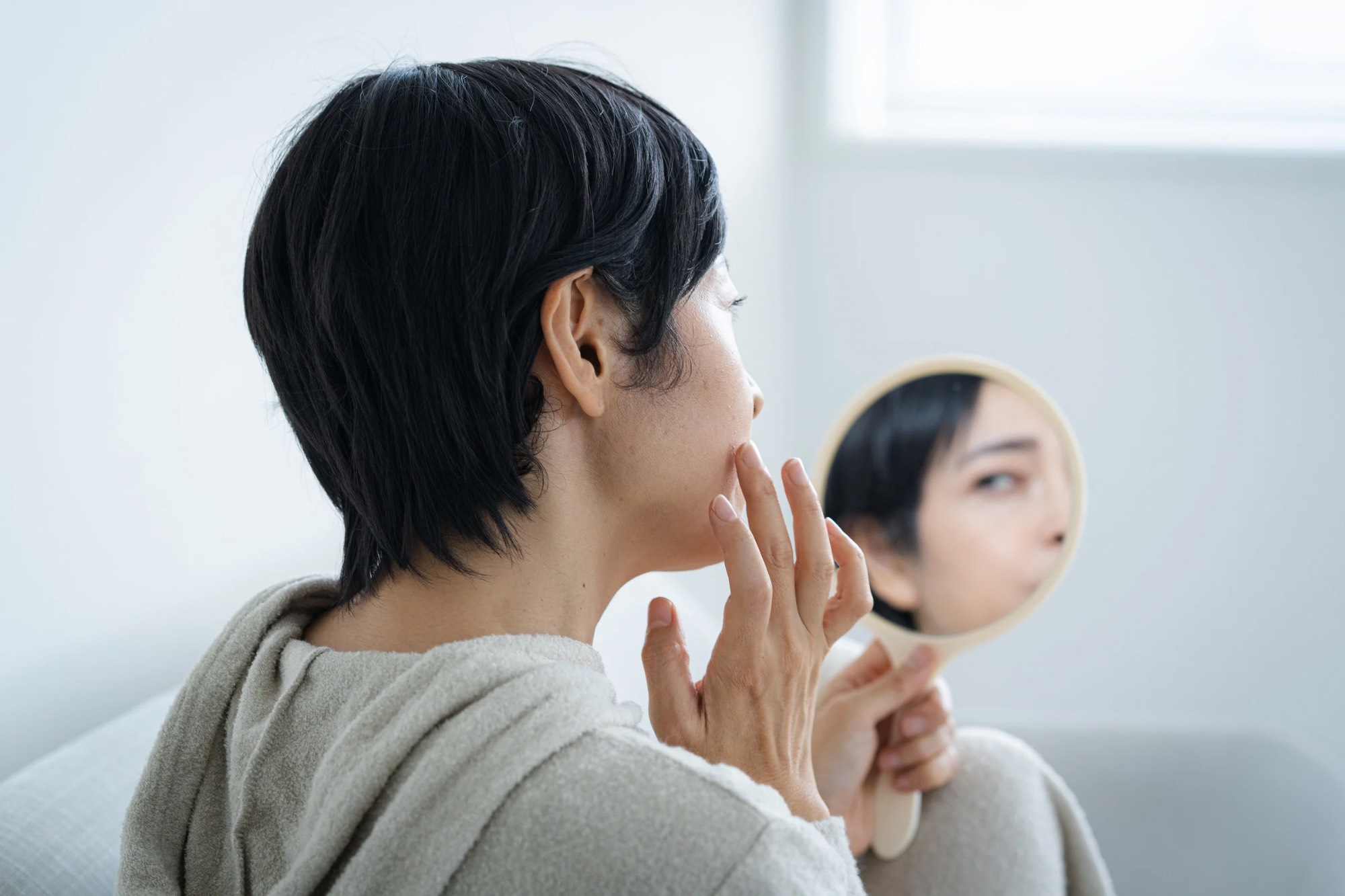 鏡をのぞき込み悩む40代女性